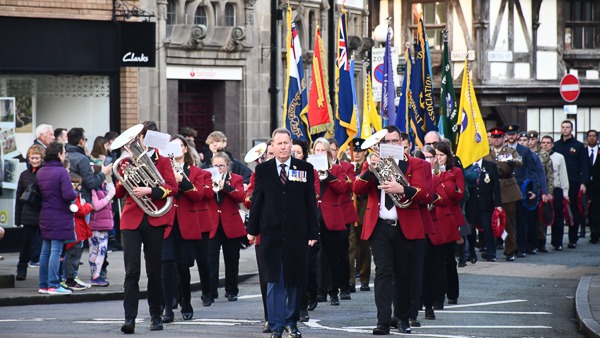 Band marching through the street with red and black unfiorms and banners